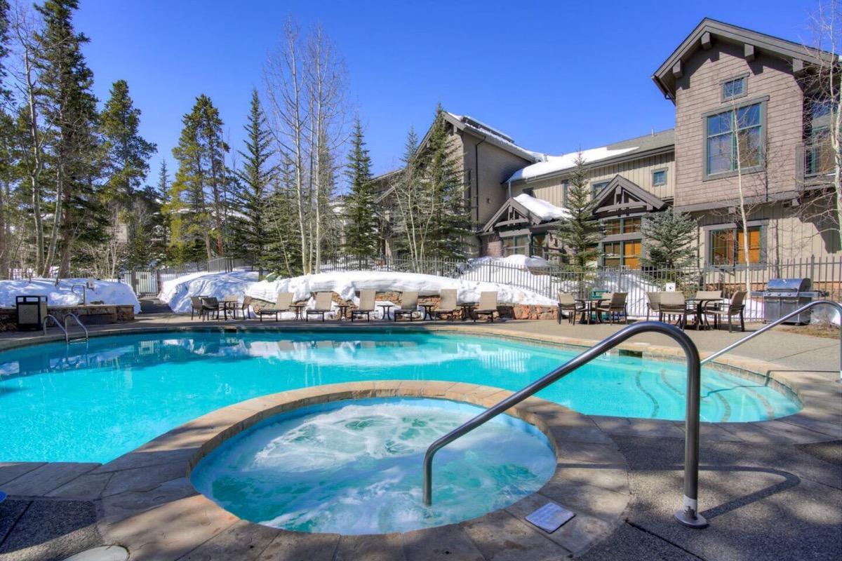 The heated outdoor pool and hot tub at Mountain Thunder Lodge in winter, snow banked around the loungers